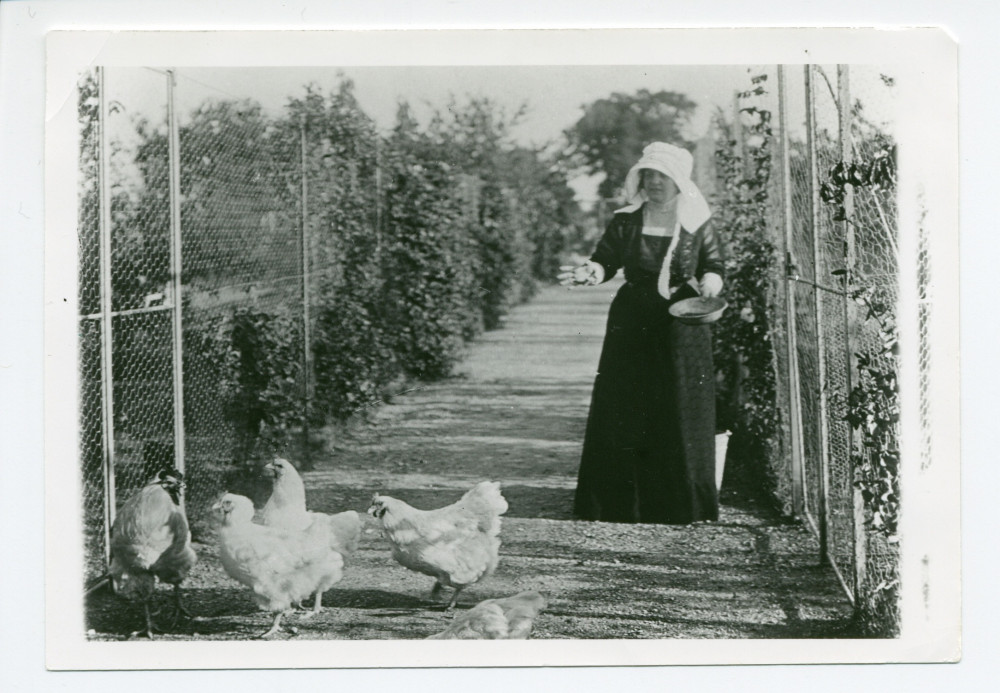 Photographie d'Hélène Paderewska nourrissant ses poules primées dans le jardin de Riond-Bosson