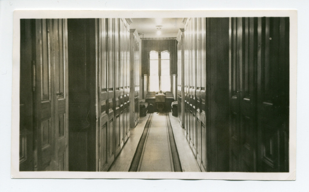 Photographie du corridor menant aux chambres des hôtes à Riond-Bosson, avec de chaque côté des armoires à linge