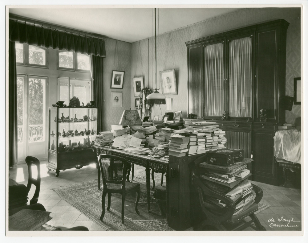 Photographie du studio de Paderewski à Riond-Bosson réalisée par l'Atelier de Jongh à Lausanne, avec au centre son bureau recouvert de documents, à gauche la collection chinoise en vitrine et à droite le prie-Dieu