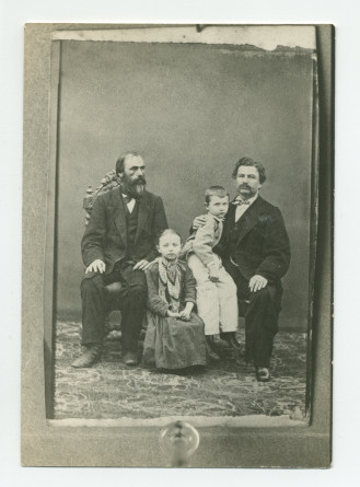 Photographie de Paderewski, âgé d'environ 10 ans, sur le genou droit de son père Jan, avec sa sœur Antonina assise au milieu et un autre homme assis à gauche (le grand-père paternel?)