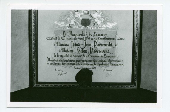 Photographie de détail de l'encadrement (reproduction?) du diplôme de citoyen d'honneur décerné à Paderewski par la Ville de Lausanne, exposé sur un piano à queue du salon de Riond-Bosson