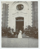 Photographie d'Hélène Paderewska, en robe blanche, regardant un chien, et d'Alfred, sur son buggy, devant l'entrée principale de Riond-Bosson