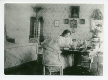 Photographie d'Hélène Paderewska écrivant dans sa chambre à coucher de Riond-Bosson (ancien décor)